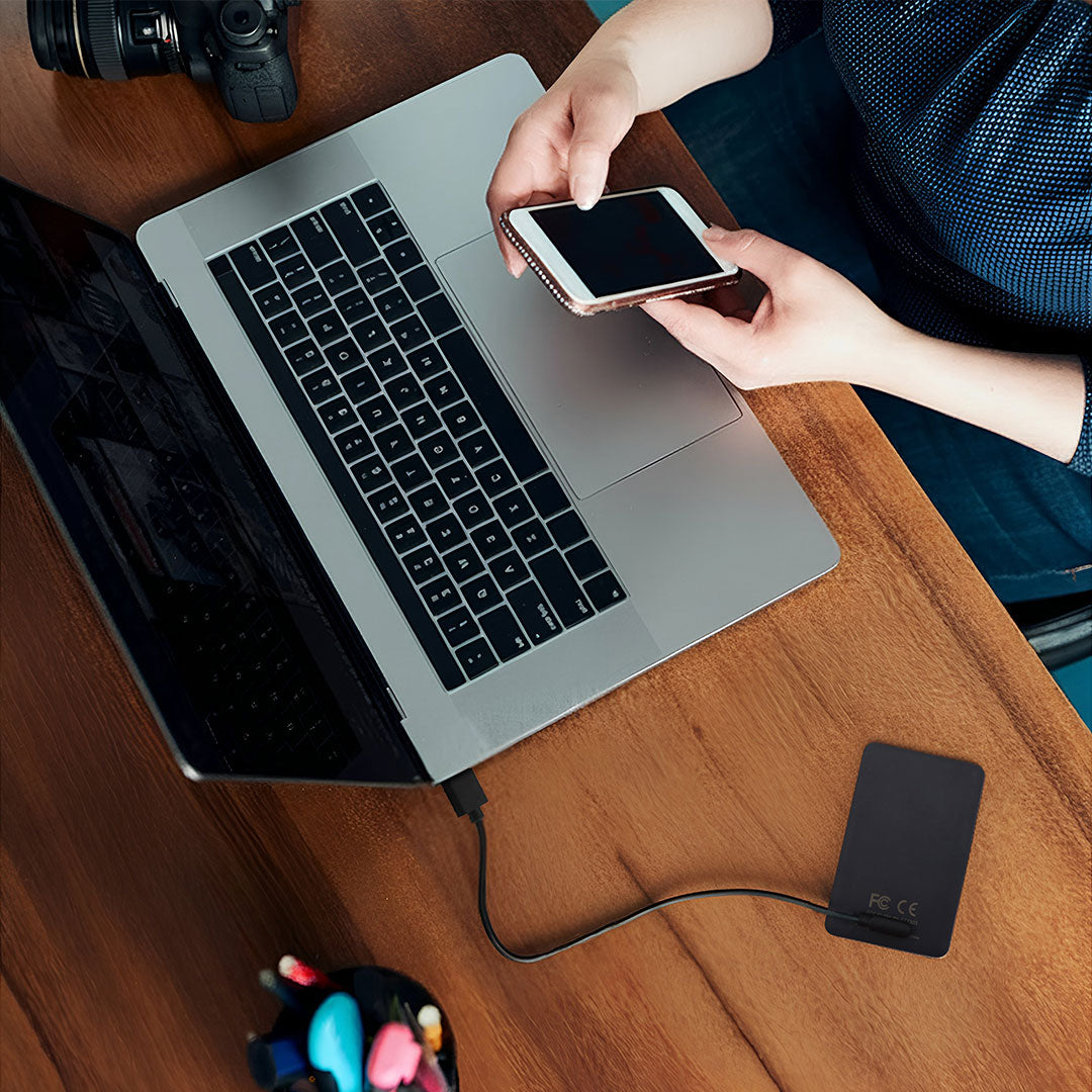 person using smartphone while working on laptop at desk,